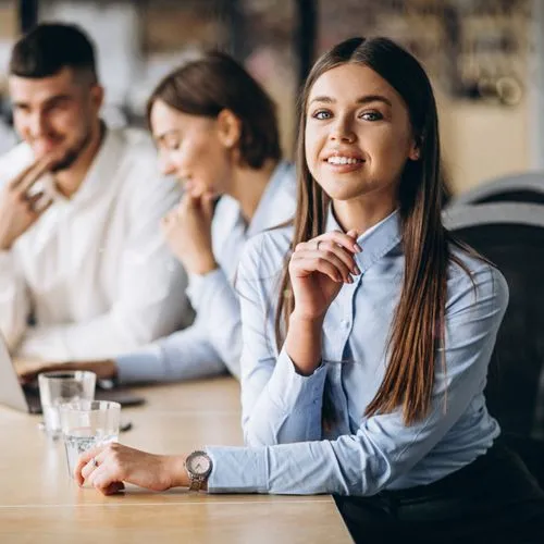 A woman working on a table with more people in the background